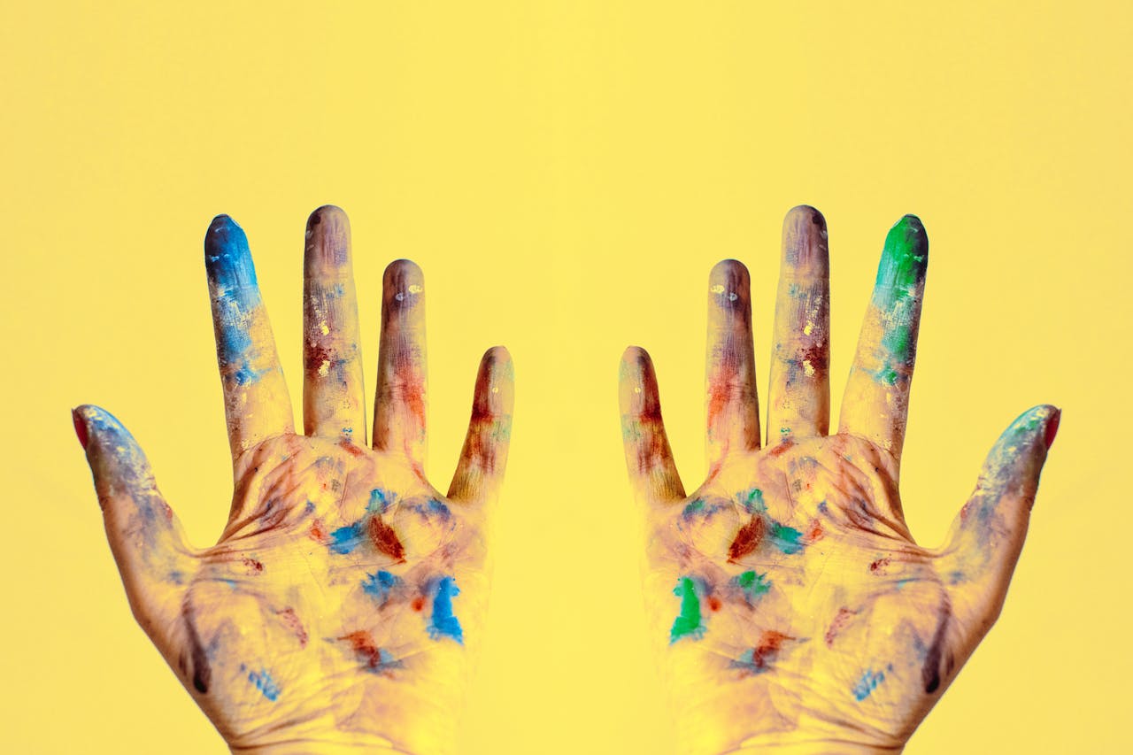 Colorful fingers spread against a bright yellow backdrop, showcasing creativity.